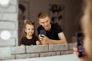 ritratto di adorabili fratelli caucasici che fanno selfie nello specchio per il trucco. concetto di famiglia, bellezza, casting e bambini foto