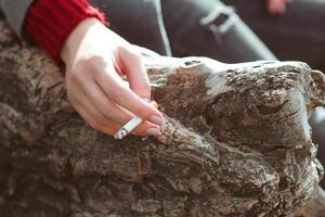 mano stressante della giovane donna con la sigaretta dall'albero foto