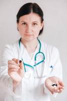 donna medico con le pillole nelle sue mani su uno sfondo bianco. prendendo vitamine o farmaci. copia, spazio vuoto per il testo foto