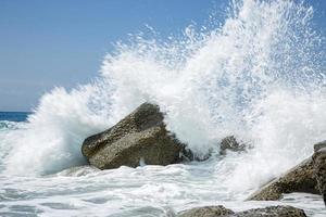 onda alta che si infrange sugli scogli della costa. foto