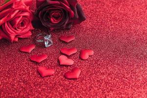 vuoi sposarmi. fede nuziale rose rosse scarlatte e molti cuori rossi su sfondo rosso glitter. concetto di matrimonio proposta di matrimonio di fidanzamento. st. cartolina di san valentino. banner il giorno di San Valentino. foto