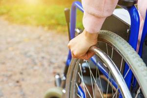 donna con handicap a mano in sedia a rotelle su strada nel parco dell'ospedale in attesa di servizi per i pazienti. ragazza paralizzata irriconoscibile su sedia per invalidi per disabili all'aperto. concetto di riabilitazione. foto
