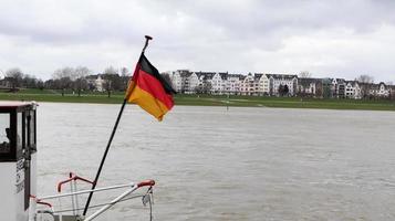 dusseldorf, germania - 20 febbraio 2020. bandiera della germania su una nave sul reno. la bandiera nazionale tedesca sul retro di una nave passeggeri vola nel vento. di linea al tempo di dusseldorf. foto