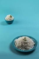 riso basmati bianco cotto in un piatto blu e una ciotola su sfondo blu foto