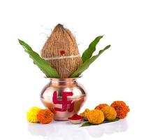 kalash di rame con cocco, foglia di mango, haldi, kumkum e dolci con decorazione di fiori di calendula su sfondo bianco. essenziale nella puja indù. foto
