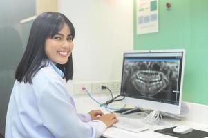dentista femminile che lavora con i raggi x dei denti sul computer portatile in clinica odontoiatrica, controllo dei denti e concetto di denti sani foto