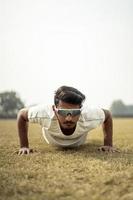 primo piano ritratto di un giovane sportivo indiano che si esercita nel campo. sportivo che fa flessioni per il riscaldamento. foto