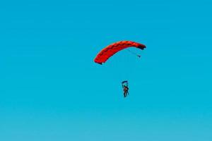 lancio con paracadute in tandem. sagoma di paracadutista che vola nel cielo blu chiaro. foto