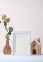 cornice per foto con ramo di eucalipto in vaso di legno e giocattolo in legno su sfondo pastello