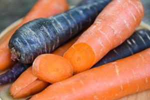 carota e carota viola sul vassoio, carota fresca per cucinare vegetariano sul tavolo di legno in cucina. foto