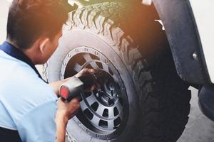 riparare o sostituire il meccanico del pick-up dell'auto del pneumatico avvitando svitando la ruota dell'auto presso il negozio della stazione di servizio di riparazione foto