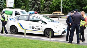 ucraina, kiev - 2 giugno 2020. le auto di pattuglia della polizia forniscono sicurezza sulle strade di kiev in ucraina. un poliziotto maschio si trova vicino alla sua auto sulla carreggiata foto