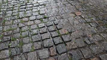 un marciapiede bagnato crea uno sfondo lucido. bellissimo sfondo di pietra grigia. strada in pietra, selciato nel centro storico durante la pioggia durante il giorno. foto