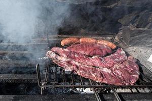 tipico asado uruguaiano e argentino cotto sul fuoco. entrana e vacio tagli di carne. accompagnato con salsiccia. foto