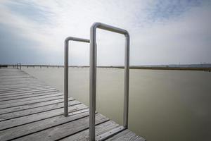 un molo in legno con scaletta per piscina in alluminio con corrimano sul Neusiedlersee in Austria. foto