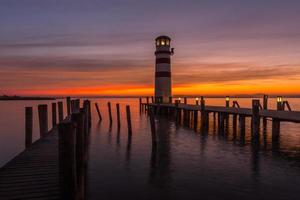 pontili in legno con faro mentre il tramonto sul lago foto