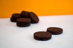 biscotti al cioccolato mantenuti in un motivo su carta bianca con sfondo giallo foto