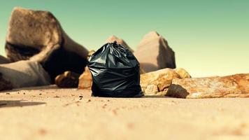 sacco della spazzatura di plastica nera pieno di spazzatura sulla spiaggia foto