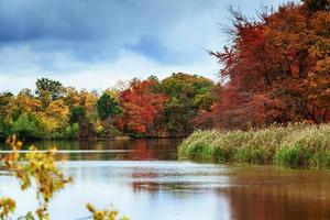 parco paesaggistico autunnale con fiume e cielo blu foto