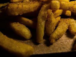 foto ravvicinata di patatine fritte su un tagliere di legno.