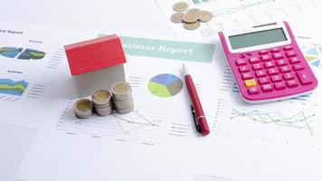 mutuo ipotecario con casa rossa e pila di monete e calcolatrice a penna per il concetto di finanza aziendale foto