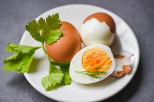 menu uova cibo uova sode in un piatto bianco decorato con foglie aneto verde e prezzemolo, tagliato a metà tuorli d'uovo per cucinare mangiare sano uova colazione foto