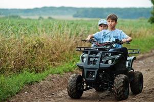 due fratelli che guidano un quad quad a quattro ruote. momenti felici dei bambini. foto