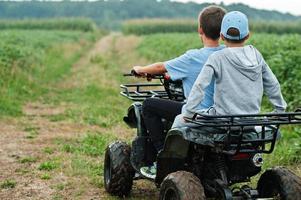 due fratelli che guidano un quad quad a quattro ruote. momenti felici dei bambini. foto