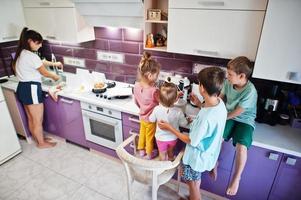 madre con bambini che cucinano in cucina, momenti felici per bambini. foto