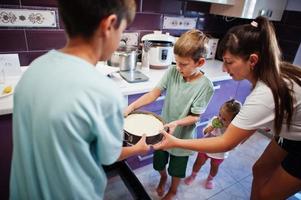 madre con bambini che cucinano in cucina, momenti felici per bambini. cheesecake al forno. foto