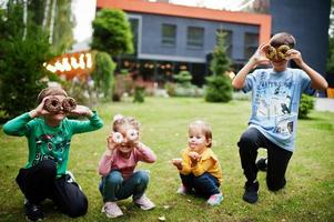 quattro bambini con ciambelle al cortile serale. gustoso cibo per ciambelle. foto