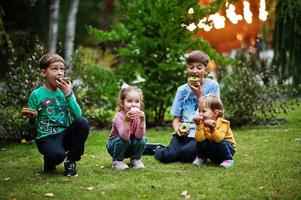 quattro bambini con ciambelle al cortile serale. gustoso cibo per ciambelle. foto