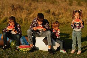 famiglia che trascorre del tempo insieme. quattro bambini mangiano anguria all'aperto. foto