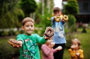 quattro bambini con ciambelle al cortile serale. gustoso cibo per ciambelle. foto