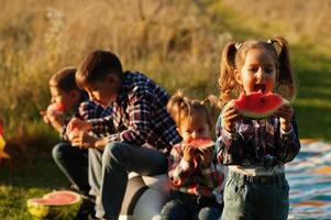 famiglia che trascorre del tempo insieme. quattro bambini mangiano anguria all'aperto. foto