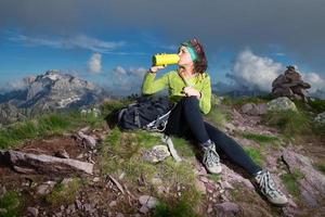 una ragazza sportiva beve dalla bottiglia d'acqua dopo aver conquistato la cima di una montagna foto