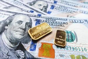 lingotto d'oro puro e qualche banconota da 100 dollari americani foto