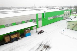 trattore che pulisce la neve nella vista dall'alto della fabbrica. foto