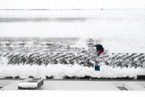 lavoratore pulisce la neve con una pala vista dall'alto. foto