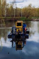 la barca per la pulizia del fiume raccoglie i rifiuti sull'acqua foto