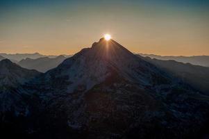 sole che sorge dietro le montagne foto