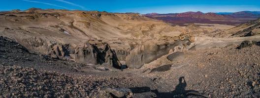 vista panoramica sul paesaggio islandese della colorata caldera vulcanica askja, nel mezzo del deserto vulcanico negli altopiani, con suolo vulcanico rosso e turchese e cielo blu, islanda foto