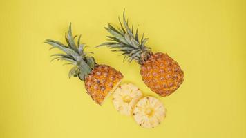 frutta di ananas e alcuni dei suoi pezzi isolati su sfondo giallo foto