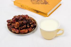 date del Corano e un bicchiere di latte isolato su uno sfondo bianco foto
