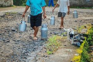 il tradizionale lavoratore lattiero-caseario o l'uomo del latte a Boyolali, in Indonesia, portano un contenitore per il latte lucido in metallo o un bollitore tradizionale dalla fattoria tradizionale foto