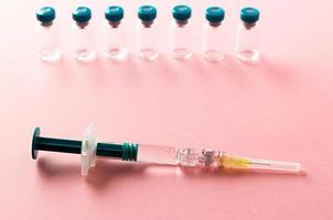 siringa con diverse fiale mediche per l'iniezione su sfondo rosa. foto