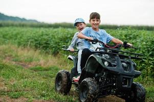 due fratelli che guidano un quad quad a quattro ruote. momenti felici dei bambini. foto