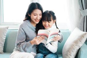 immagine di madre e figlia seduta sul divano a leggere un libro foto