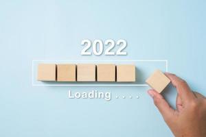 caricamento del nuovo anno dal 2021 al 2022 con la barra di avanzamento manuale del cubo di legno foto
