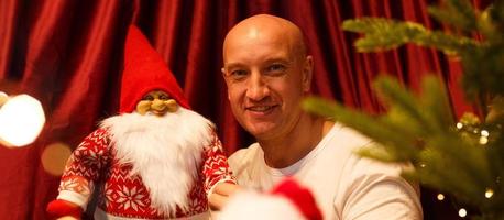 ritratto di un uomo calvo che tiene un giocattolo di babbo natale all'albero di natale foto